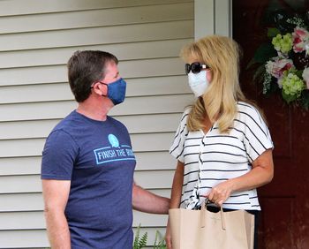 Full length of young couple standing outdoors wearing masks