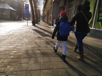 Rear view of people walking on sidewalk