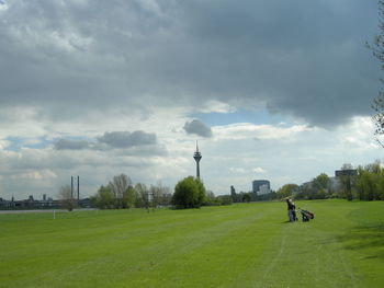 People playing golf on grassy field with city in background