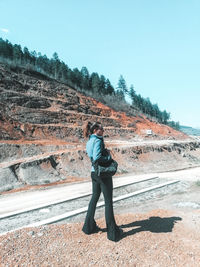 Rear view of man standing on mountain against clear sky