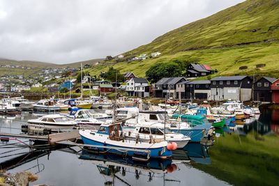 Boats moored at harbor against sky