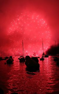 Silhouette boats moored in sea against sky at night