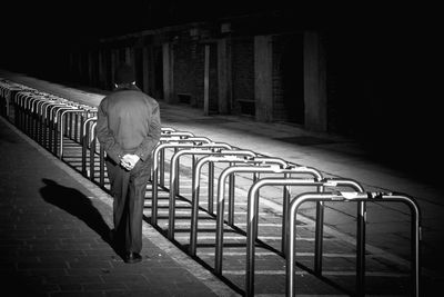 Rear view of man walking by bicycle racks on street