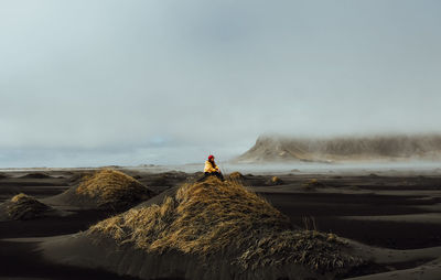 Man standing on rock by sea against sky