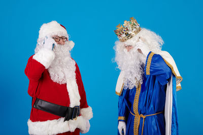 Portrait of woman wearing santa claus costume standing against blue background