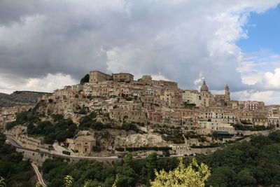 Buildings in city against cloudy sky