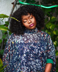 Young woman with curly hair standing by plants