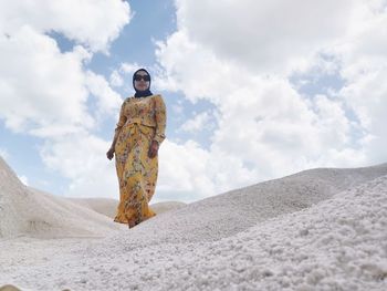 Low angle view of woman standing on sand against sky