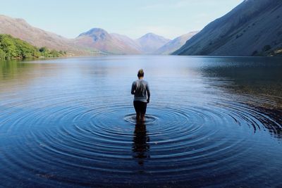 Scenic rear view of young woman walking in lake