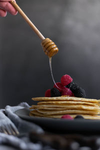 Pouring raw honey over homemade crepes on table, dark food photography