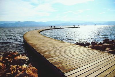 Pier on sea against cloudy sky