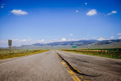 Empty road along countryside landscape against sky