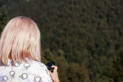 Rear view of woman photographing outdoors