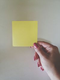 Cropped image of holding adhesive note against gray background