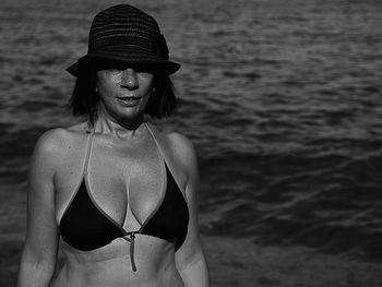 Portrait of woman in bikini standing at beach against sky