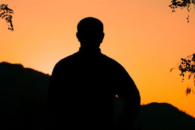 Rear view of silhouette man against sunset sky