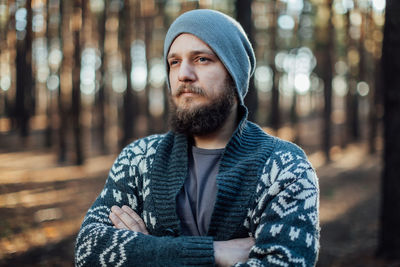 Thoughtful young man standing in forest