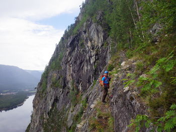 Man climbing on rock against sky