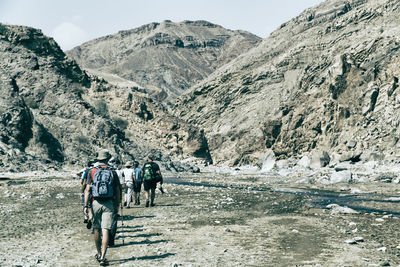 Rear view of people walking on mountain road