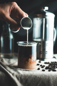 Close-up of hand pouring coffee in cup