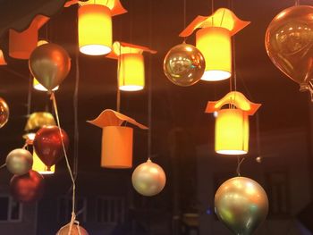 Low angle view of illuminated pendant lights hanging on ceiling