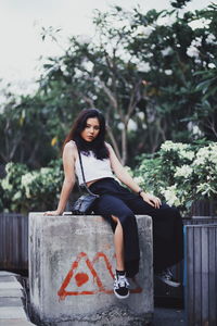 Portrait of woman sitting against tree