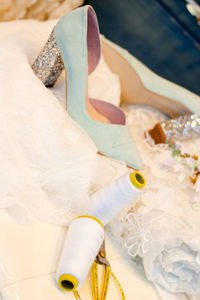 Close-up of shoes and spools with wedding dress