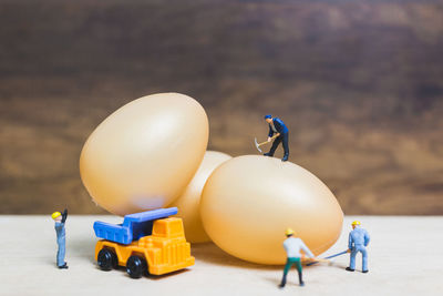 Close-up of figurines with eggs and toy trucks on table