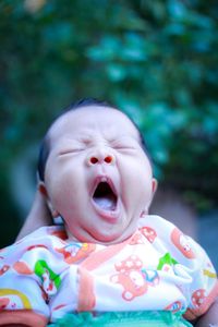 Close-up of baby girl yawning outdoors