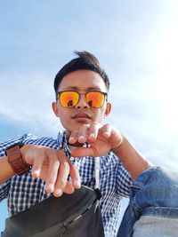 Portrait of young man wearing sunglasses against sky