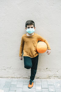 Little boy with a ball and protective mask. coronavirus concept.