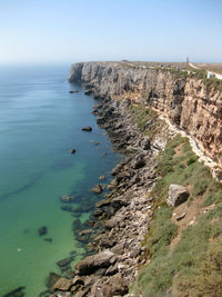 Cliff by sea against sky