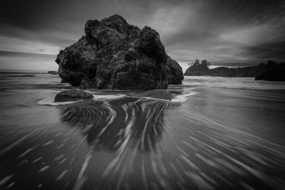 Rock formation on beach against sky