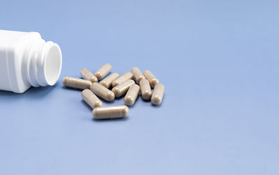 Close-up of pills spilling from bottle against blue background