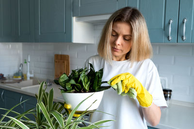 Woman gardening takes care house plants at kitchen