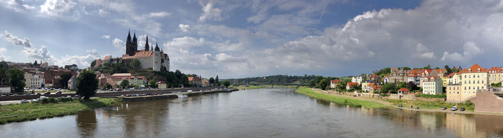 Panoramic view of buildings by river against sky in city