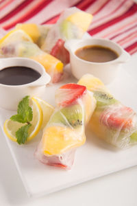 Close-up of fruit spring rolls served on plate at restaurant table