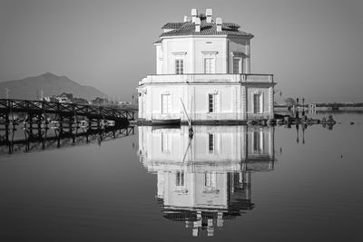 Building reflecting on river against clear sky