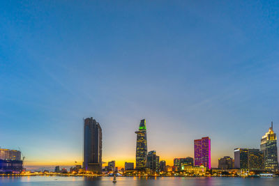 Sea by modern buildings against blue sky