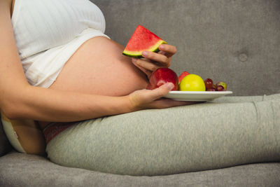 Midsection of woman eating fruit