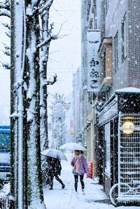 People walking on snow covered street in city