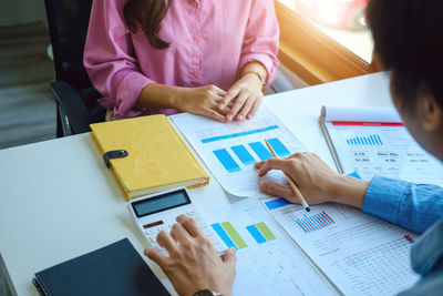 Midsection of business colleagues working on table