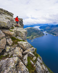 High angle view of fjords with hiker standing on top