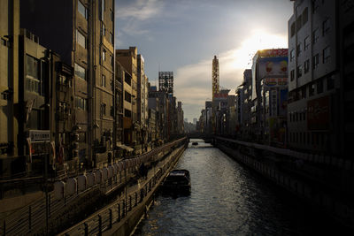 Canal amidst buildings in city against sky during sunset