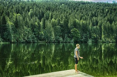 Woman looking at lake against trees in forest