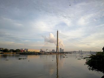 Factory by river against sky