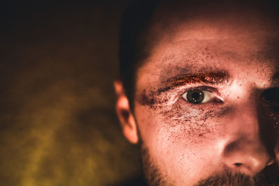 Close-up portrait of man with glitter eye make-up