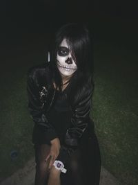 Portrait of woman with face paint sitting on field