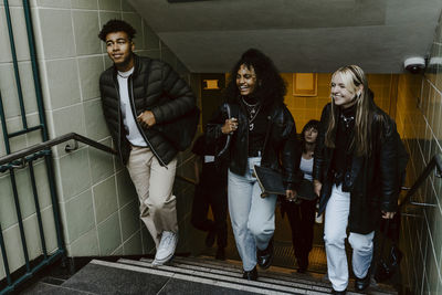 Smiling friends climbing staircases at subway