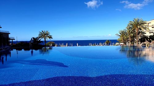 Swimming pool by sea against blue sky